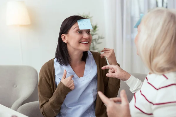 Uitbundige oudere vrouw en verzorger puzzel op te lossen — Stockfoto