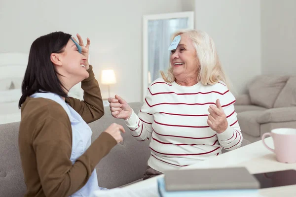 Jovial elder woman and caregiver playing together — Stock Photo, Image