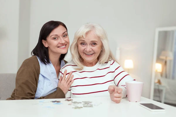 Mujer anciana energética y cuidador recogiendo rompecabezas — Foto de Stock