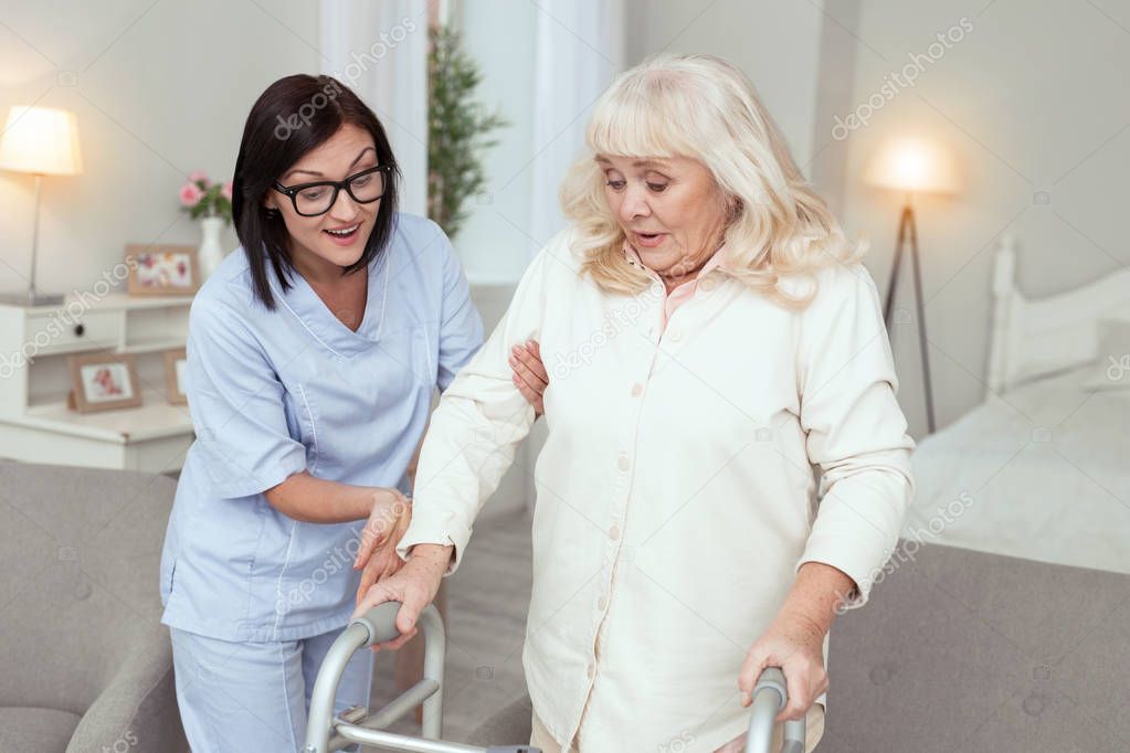 Positive nurse coming with aid to elder woman