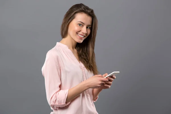 Freudige junge Frau mit ihrem Smartphone — Stockfoto