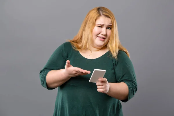 Frumoasă femeie obeză arătând spre smartphone-ul ei — Fotografie, imagine de stoc