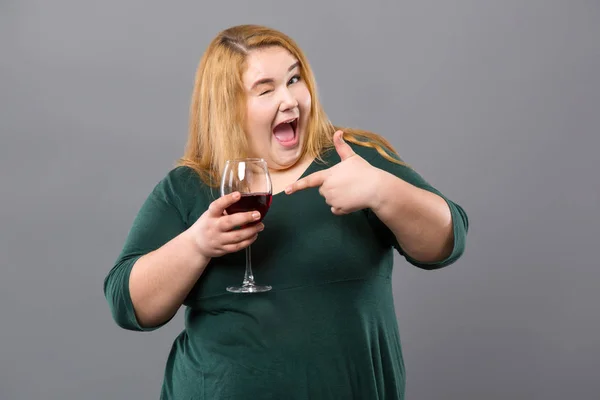 Весела мила жінка вказує на келих з вином — стокове фото