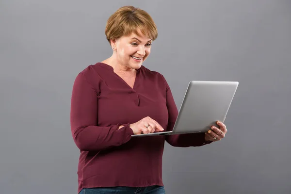 Позитивна гарна жінка використовує свій ноутбук — стокове фото