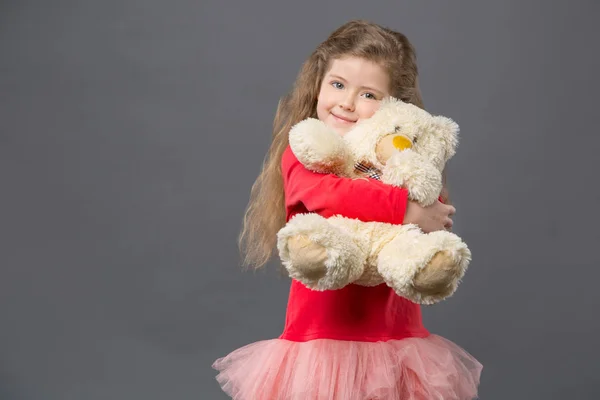 Delighted cute girl hugging her fluffy bear — Stock Photo, Image