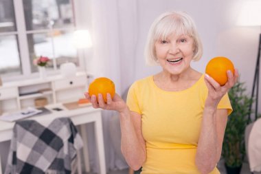 İki portakal tutan neşeli yaşlı kadın