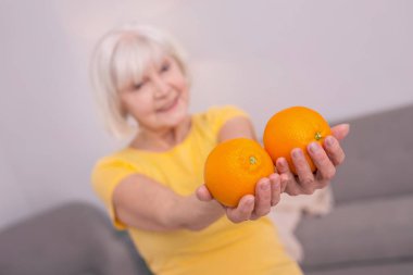 İki portakal gösterilen hoş yaşlı kadın