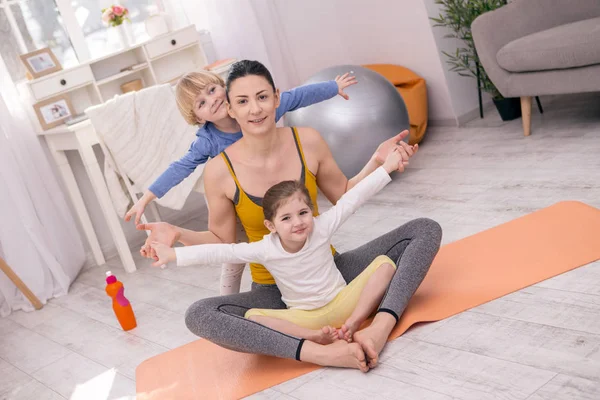Alegre madre sentada con sus hijos en la alfombra —  Fotos de Stock