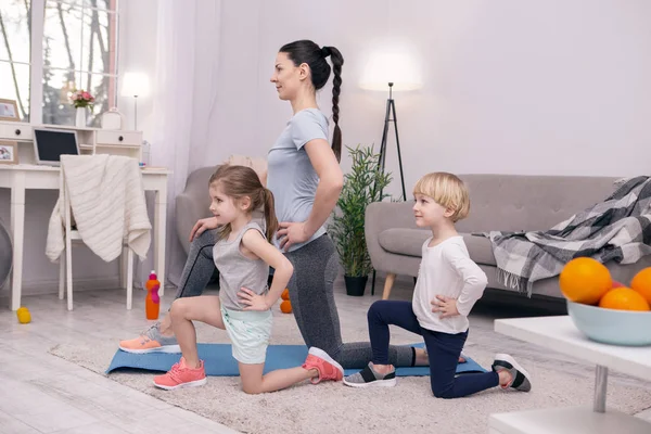 Inspirerad mamma träning med hennes små barn — Stockfoto