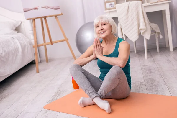 Femme âgée optimiste posant tout en pratiquant le yoga — Photo