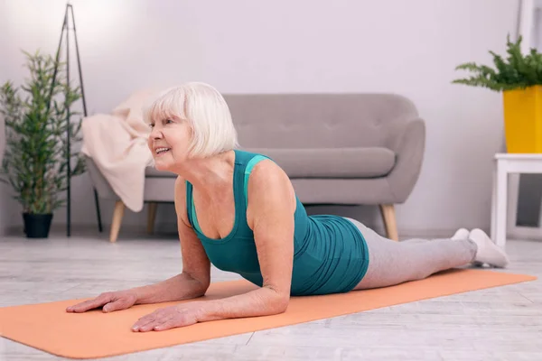 Pleasant senior woman exercising muscles of her neck