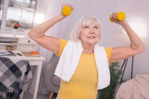 ダンベルを持ち上げる陽気な年配の女性 — ストック写真