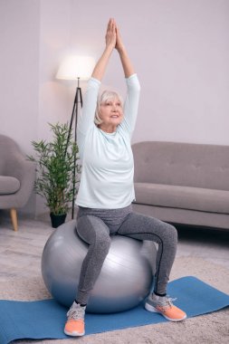 Ağaç poz egzersiz topu üzerinde oturan hoş kadın kıdemli
