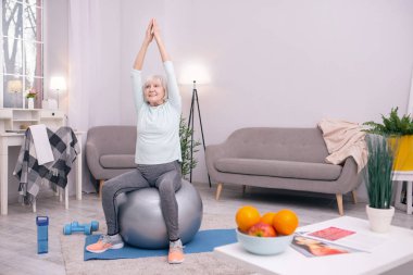 Ağaç poz yoga topu üzerinde oturan oldukça yaşlı kadın
