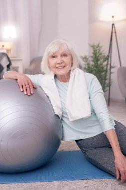Yoga topu yakınındaki otururken gülümseyen kadın iyimser kıdemli