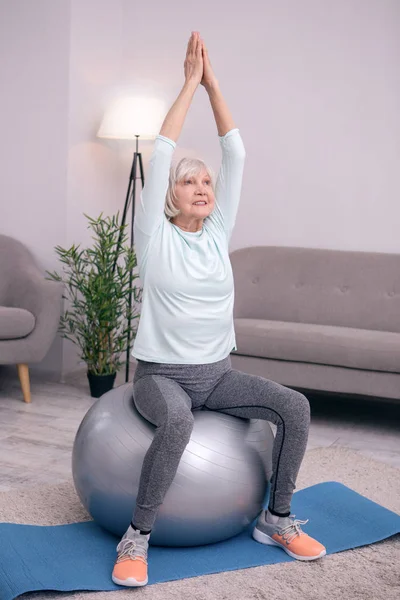 Ağaç poz egzersiz topu üzerinde oturan hoş kadın kıdemli