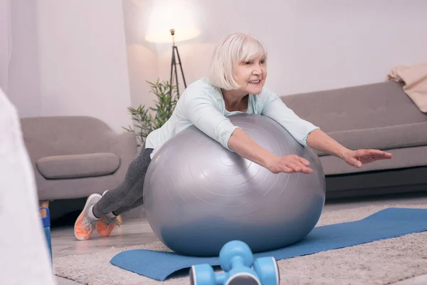 Agradável mulher idosa deitada na bola de exercício — Fotografia de Stock