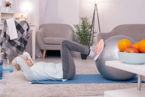 Mekik yoga topu yardımıyla yapıyor ince yaşlı kadın