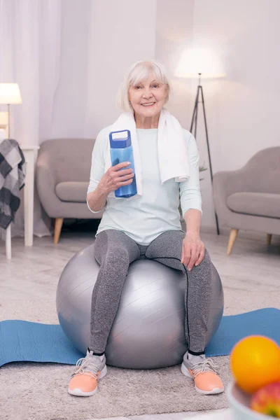 Trevlig äldre kvinna poserar med vattenflaska efter träningspass — Stockfoto