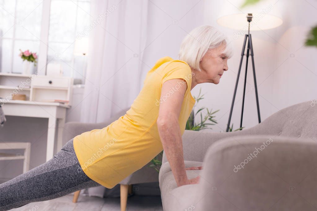Slim elderly woman doing push-ups