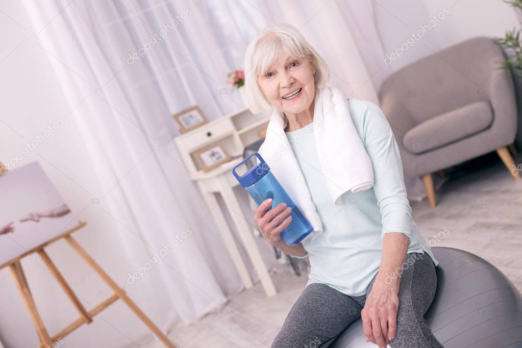 Cheerful senior woman having water after exercising