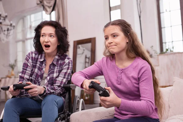 Alegre mujer y chica incapacitada compitiendo en videojuegos —  Fotos de Stock