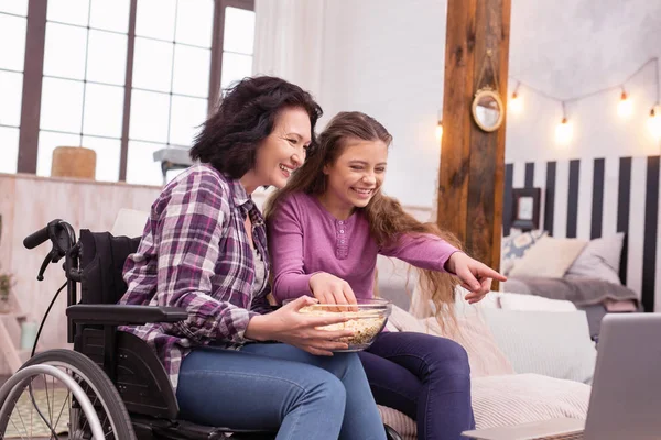 Optimistic incapacitated woman and girl viewing comedy — Stock Photo, Image