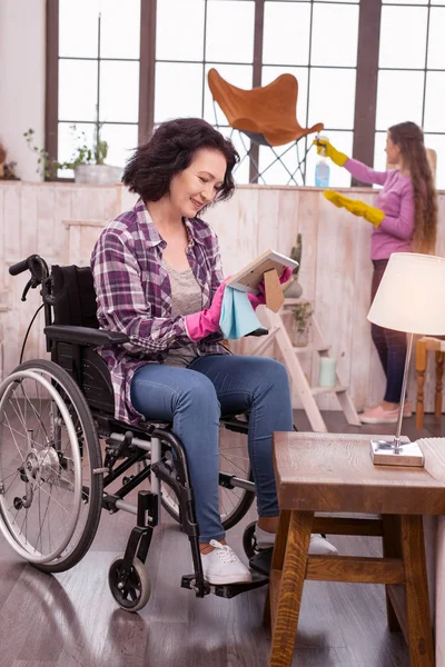 Feliz mujer inmóvil limpiando polvo — Foto de Stock