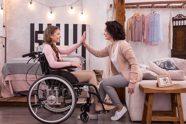 Attractive woman livening up disabled girl — Stock Photo, Image