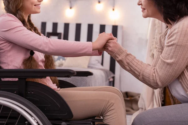 Pleasant woman and disabled girl joining hands — Stock Photo, Image