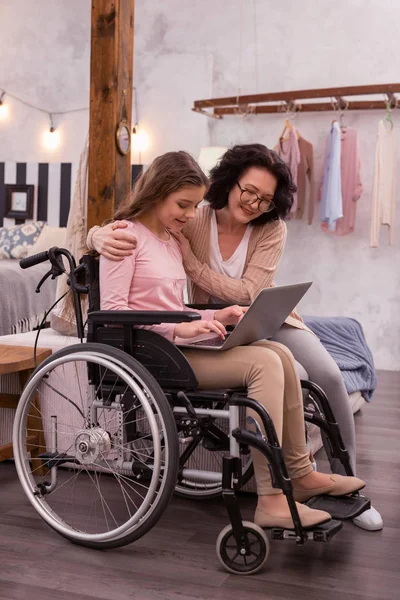 Joyeuse femme et fille handicapée utilisant un ordinateur portable — Photo
