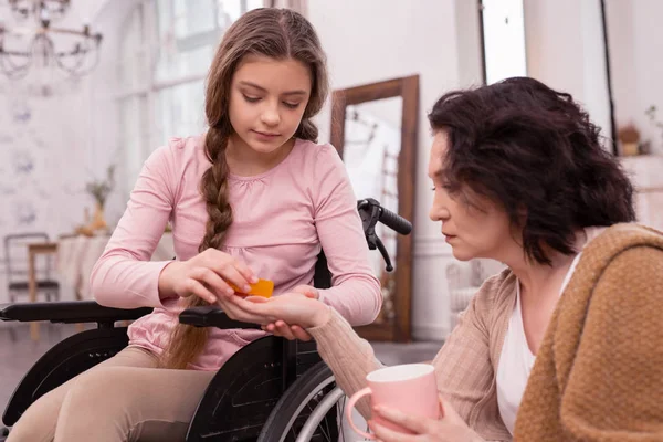 Earnest handicapped girl giving pills to woman — Stock Photo, Image