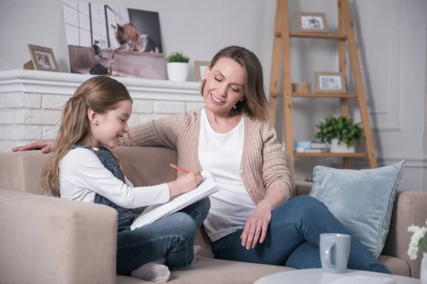 Inspired mother and daughter sitting on the sofa — Stock Photo, Image