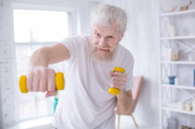 Yaşlı adam jabs dumbbells ile pratik sakallı