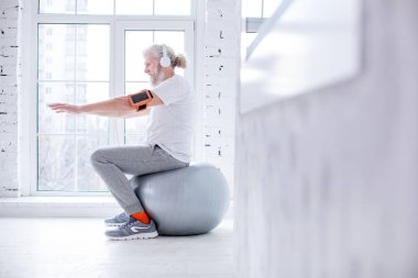 Yoga topu üzerinde oturan ve müzik dinlemek hoş yaşlı adam