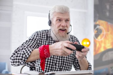 White-haired senior man being excited about playing video game clipart