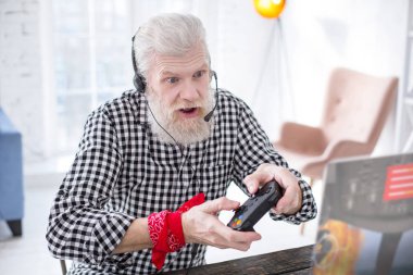 White-haired elderly man playing video game excitingly clipart