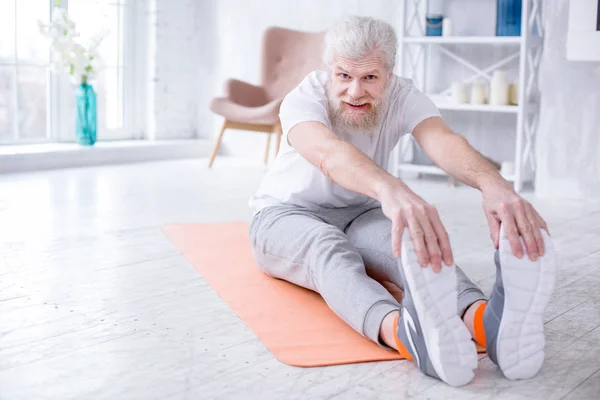 Handsome elderly man bending forward and touching toes — Stock Photo, Image