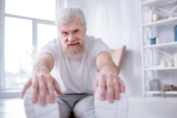 Affascinante uomo anziano in posa mentre fa stretching — Foto Stock