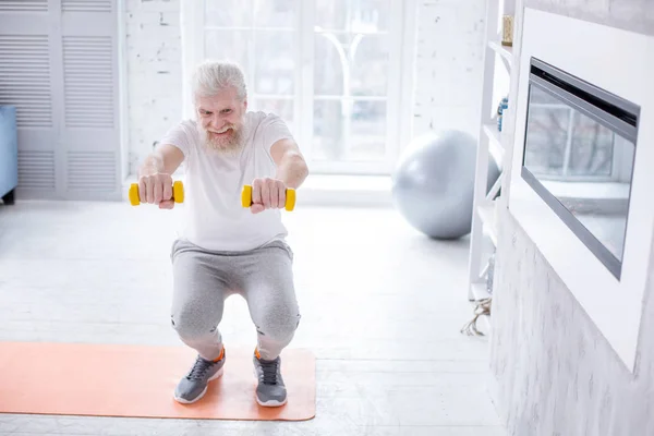 Vacker äldre man holding hantlar och göra knäböj — Stockfoto