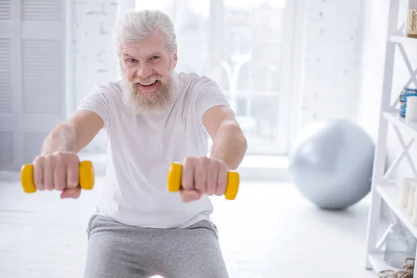 Pria ceria menyeringai sambil berolahraga dengan dumbbells — Stok Foto