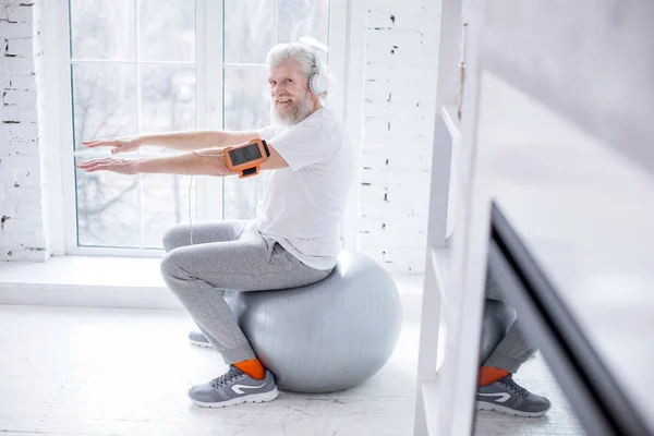 Agradable anciano posando mientras hace ejercicio y escucha música —  Fotos de Stock