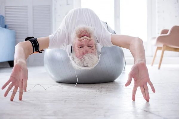 Joyful homem sênior ouvir música na bola de ioga — Fotografia de Stock