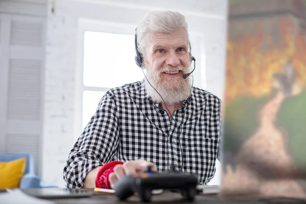 Bájos idősebb ember játszik számítógépes játék, és mosolyogva — Stock Fotó