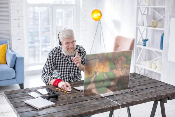 Upbeat elderly man chatting with friends while playing game