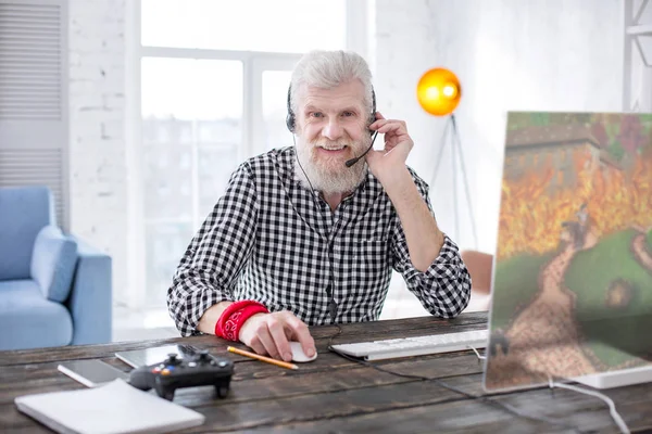 Charming elderly man posing while playing online game