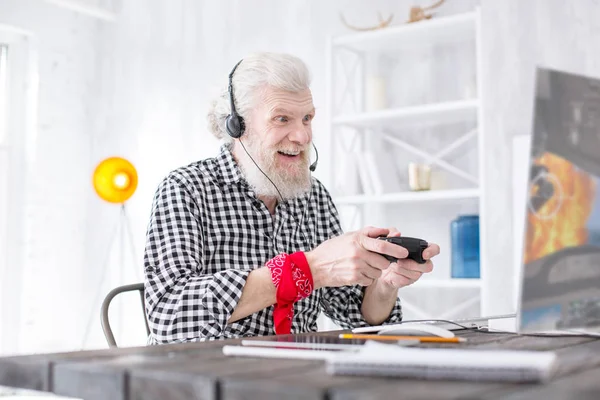 Cheerful senior man being focused on video game