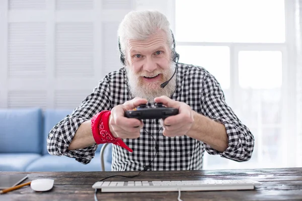 Homem idoso alegre usando controlador de jogo enquanto joga — Fotografia de Stock