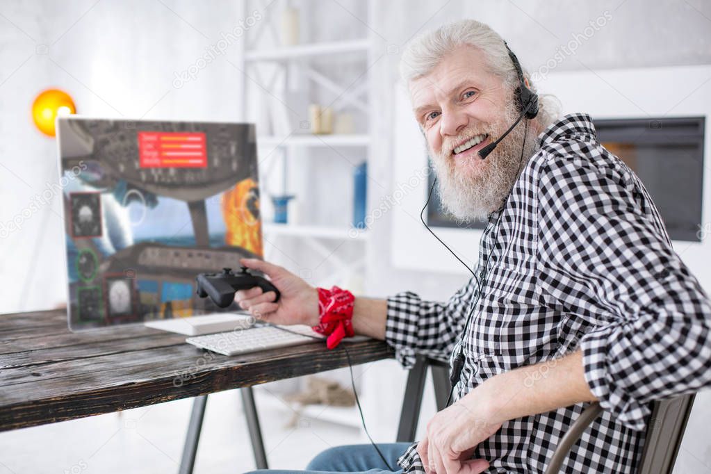 Joyful elderly man posing while taking break at playing game