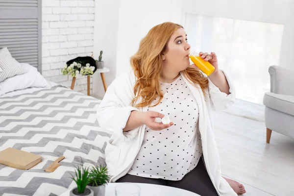 Mujer gorda concentrada bebiendo su jugo — Foto de Stock